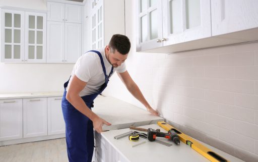 Worker installing new countertop in modern kitchen